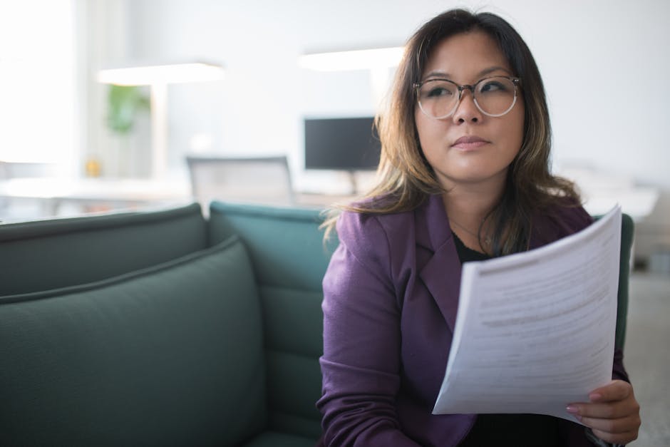 Asian businesswoman in office holding documents, expressing confidence and professionalism.