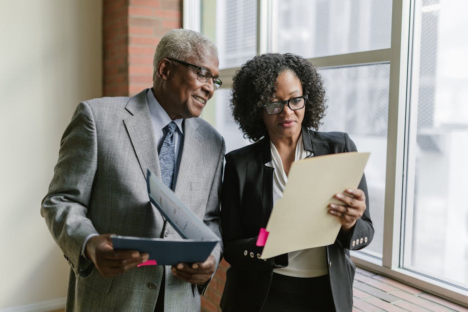 Two business professionals reviewing documents in a corporate office setting.